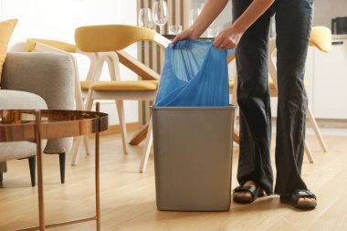 Ev hanımı çöpleri atıyor, evdeki çöp kutusundan plastik çöp torbalarını alıyor.