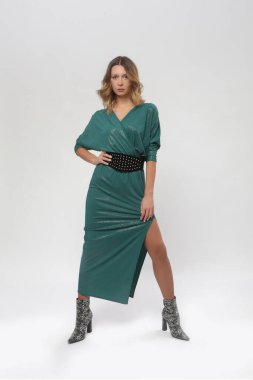 Stüdyoda çekilmiş yeşil elbiseli genç bir kadın modelin fotoğrafları.