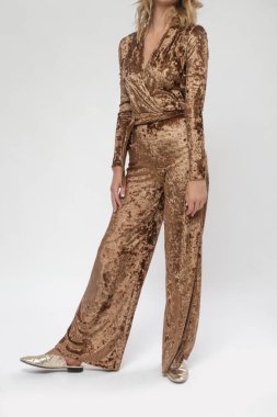 Stüdyo fotoğraflarının serisi. Altın renkli peluş tulumlu kadın manken.