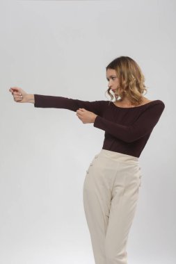 Serie of studio photos of young female model wearing comfortable basic smart casual outfit, burgundy viscose boat neckline shirt and beige trousers clipart