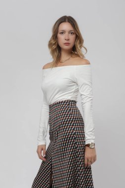 Stüdyo fotoğrafları, beyaz gömlek ve yırtık desenli midi etek giyen kadın modeller.