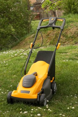Bahçedeki yeşil çimlerin üzerinde sarı çim biçme makinesi