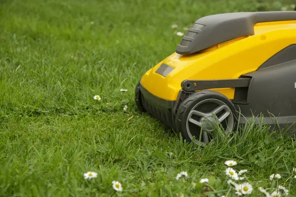 stock image Yellow lawn mower on the spring green grass in the yard