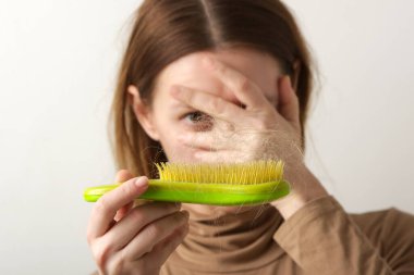 Woman holding detangler hair brush full of hair that has fallen out, loss hair problem clipart
