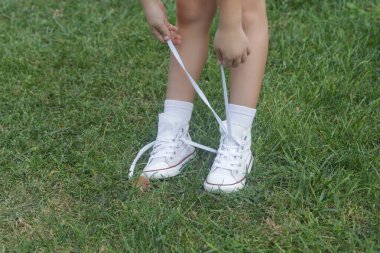 Ayakkabı bağlayan çocuk. Ayakkabı bağcıklarını bağlamaya çalışan küçük bir kız. Çocuk iyi motor becerileri öğreniyor.