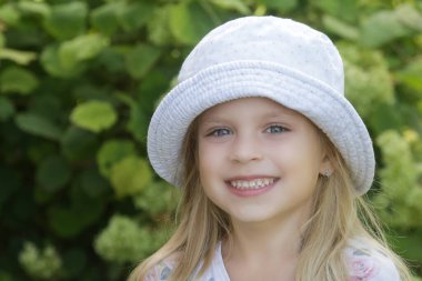 Kovalı şapkalı mutlu küçük kızın açık hava portresi.