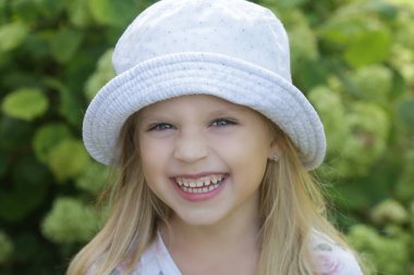 Kovalı şapkalı mutlu küçük kızın açık hava portresi.