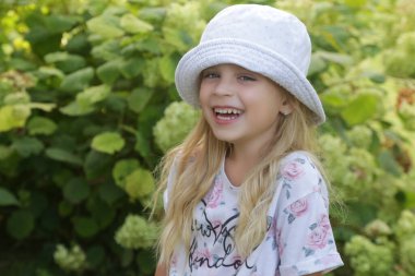 Kovalı şapkalı mutlu küçük kızın açık hava portresi.
