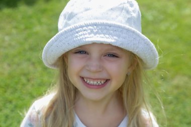 Kovalı şapkalı mutlu küçük kızın açık hava portresi.