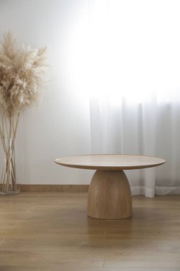 Yuvarlak ahşap sehpa ve vazoda otlar, ev dekorasyonu konsepti..