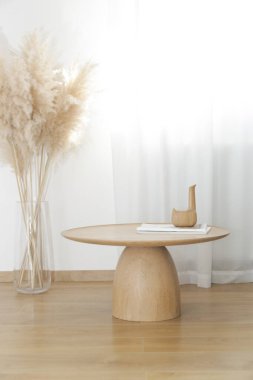 Yuvarlak ahşap sehpa ve vazoda otlar, ev dekorasyonu konsepti..