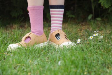 Çocuk farklı bir çift çorap giyiyor. Dışarıda dikilen uyumsuz çorapların içinde çocuk ayakları. Down sendromu farkındalık konsepti, garip çoraplar günü, zorbalık karşıtı hafta.