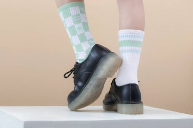 Kid wears different pair of socks. Child foots in mismatched socks, studio photography. Down syndrome awareness concept, odd socks day, anti-bullying week. clipart