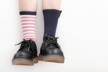 Çocuk farklı bir çift çorap giyiyor. Uyumsuz çoraplar, stüdyo fotoğrafçılığı. Down sendromu farkındalık konsepti, garip çoraplar günü, zorbalık karşıtı hafta.