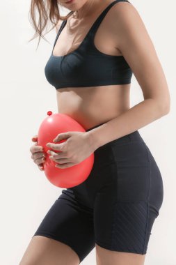 Balon tutan genç bir kadın mide şişmesi, şişkinlik ve regl krampları konseptine işaret ediyor.