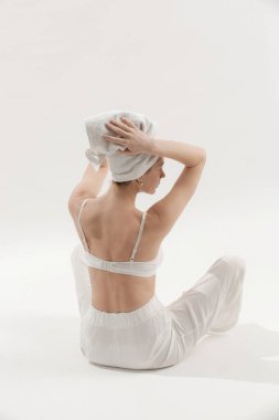 Beyaz pamuklu sutyen, pantolon ve havluyla stüdyoda poz veren güzel bir kadın. Pozitif ve mutlu bir bayanın sabah keyfi. Refah ve kendine bakım kavramı.