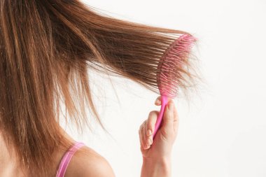 Saç bakımı. Esmer kadının saçlarını plastik çözücü saç fırçasıyla taramasını yakından izleyin..