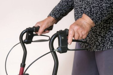 Yürüyen engelliler. Rehabilitasyon yürütecine yaslanan yaşlı engelli kadına yakın çekim. Yaşlı kadın elleriyle yürütecini itiyor..