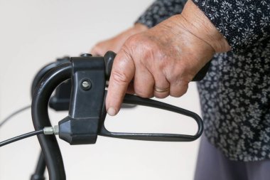 Yürüyen engelliler. Rehabilitasyon yürütecine yaslanan yaşlı engelli kadına yakın çekim. Yaşlı kadın elleriyle yürütecini itiyor..