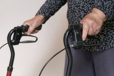 Yürüyen engelliler. Rehabilitasyon yürütecine yaslanan yaşlı engelli kadına yakın çekim. Yaşlı kadın elleriyle yürütecini itiyor..