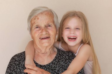 Mutlu aile, çocuk ve büyük büyükanne kucaklaşır, rahatlar, gülümser, sever ve bağlanır, evde mutlu ve mutlu bir şekilde sevgi ve şefkat gösterirler.