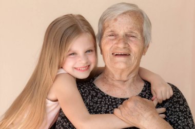 Mutlu aile, çocuk ve büyük büyükanne kucaklaşır, rahatlar, gülümser, sever ve bağlanır, evde mutlu ve mutlu bir şekilde sevgi ve şefkat gösterirler.