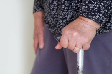 Yürüyen engelliler. Yürüme çubuğuna yaslanmış yaşlı engelli kadına yakın durun. Yaşlı kadının elleri baston tutuyordu..