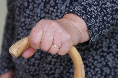 Yürüyen engelliler. Yürüme çubuğuna yaslanmış yaşlı engelli kadına yakın durun. Yaşlı kadının elleri baston tutuyordu..