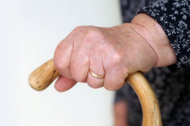 Yürüyen engelliler. Yürüme çubuğuna yaslanmış yaşlı engelli kadına yakın durun. Yaşlı kadının elleri baston tutuyordu..
