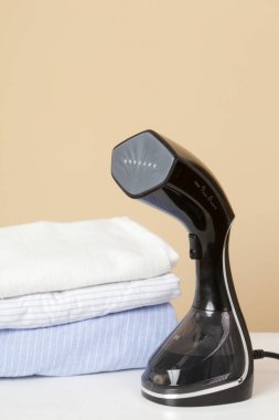 Kalın giysili vapur. Dikey vapuru ütüye hazır kıyafetlerle kapatın. Hızlı ve kolay ütüleme kavramı. 