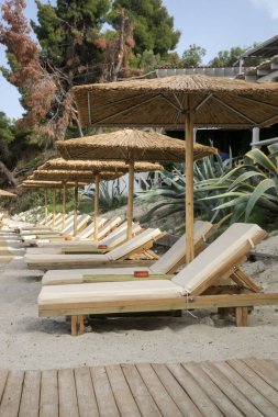  Boş plaj, saman şemsiyeler ve tahta güneşlikler.