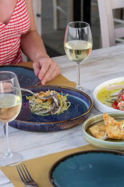 Genç bir kadın Akdeniz restoranında yemek yiyor. Masada çeşitli yemekler var..