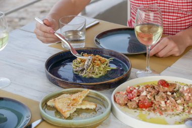 Genç bir kadın Akdeniz restoranında yemek yiyor. Masada çeşitli yemekler var..