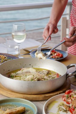 Genç bir kadın Akdeniz restoranında yemek yiyor. Masada çeşitli yemekler var..