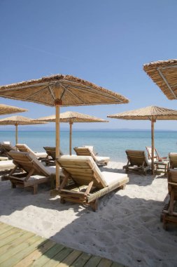 Boş plaj, saman şemsiyeler ve tahta güneşlikler.