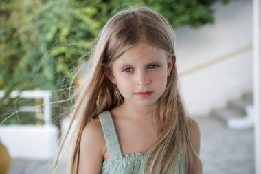 7 yaşındaki tatlı bir kızın samimi portresi. Uzun sarı saçlı ve keten gömlekli.