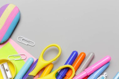 Gri arka planda çeşitli ofis ve okul malzemeleriyle okul konseptine geri dönüyoruz..