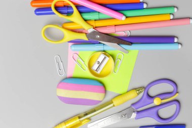 Gri arka planda çeşitli ofis ve okul malzemeleriyle okul konseptine geri dönüyoruz..