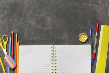 Siyah karatahta arka planında çeşitli ofis ve okul malzemeleriyle okul konseptine geri dönelim..