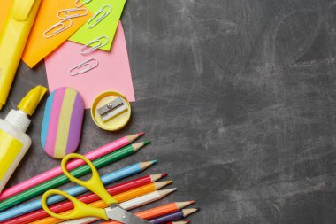 Siyah karatahta arka planında çeşitli ofis ve okul malzemeleriyle okul konseptine geri dönelim..