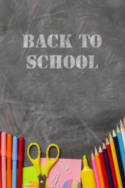 Siyah karatahta arka planında çeşitli ofis ve okul malzemeleriyle okul konseptine geri dönelim..