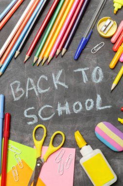 Siyah karatahta arka planında çeşitli ofis ve okul malzemeleriyle okul konseptine geri dönelim..