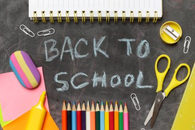 Siyah karatahta arka planında çeşitli ofis ve okul malzemeleriyle okul konseptine geri dönelim..