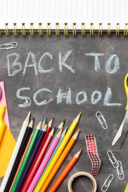 Siyah karatahta arka planında çeşitli ofis ve okul malzemeleriyle okul konseptine geri dönelim..