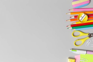 Gri arka planda çeşitli ofis ve okul malzemeleriyle okul konseptine geri dönüyoruz..