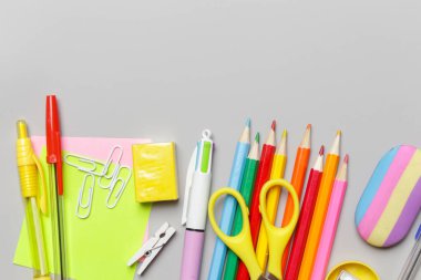 Gri arka planda çeşitli ofis ve okul malzemeleriyle okul konseptine geri dönüyoruz..