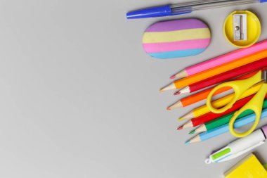 Gri arka planda çeşitli ofis ve okul malzemeleriyle okul konseptine geri dönüyoruz..