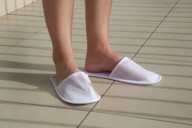 Balkonda beyaz otel terliklerinin içinde ayaklar