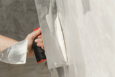 Duvarı macun bıçağıyla sıva yapan kadın. Firewall yüzeyi ve resim hazırlığı. DIY konut geliştirme projesi.