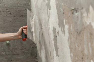 Duvarı macun bıçağıyla sıva yapan kadın. Firewall yüzeyi ve resim hazırlığı. DIY konut geliştirme projesi.